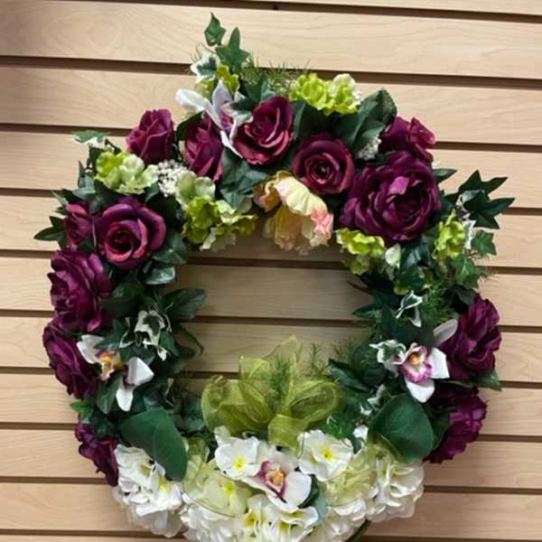 Floral wreath with purple roses and white flowers on a wooden wall