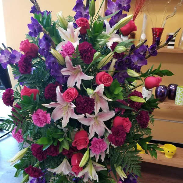 Large standing arrangement of pink roses, lilies, and purple flowers