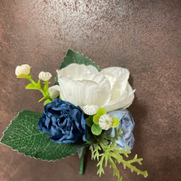 Small blue and white floral boutonniere with green leaves