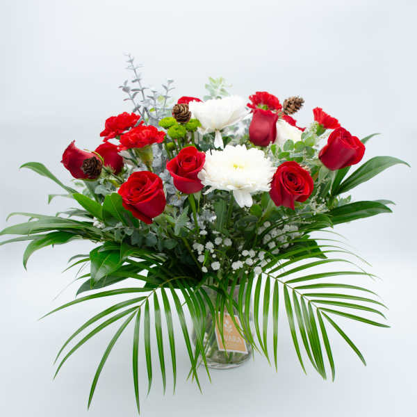 Red roses and white blooms in a glass vase with palm fronds