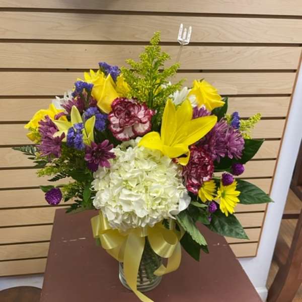Colorful mixed bouquet in a glass vase with a yellow ribbon