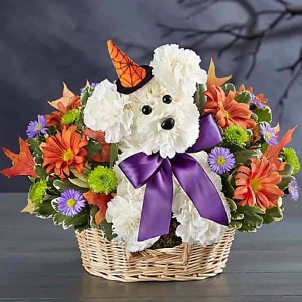 White teddy bear in a wicker basket surrounded by orange and purple flowers