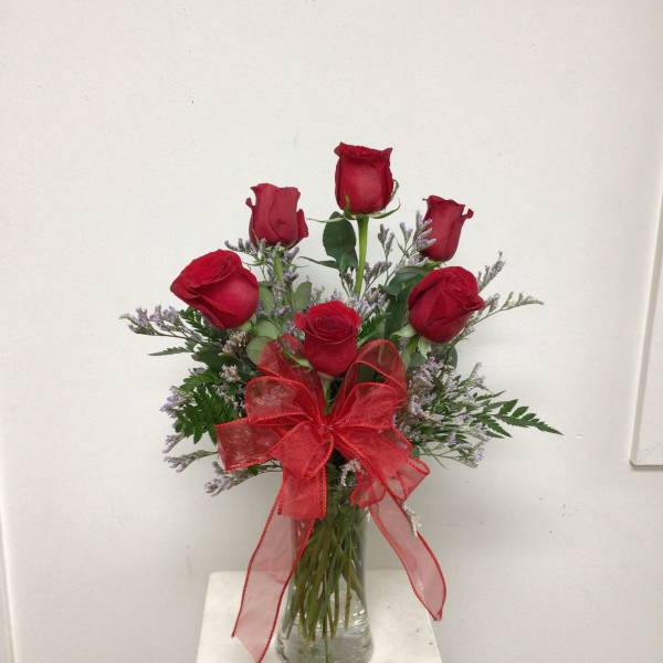 Red roses in a clear glass vase with a red ribbon bow