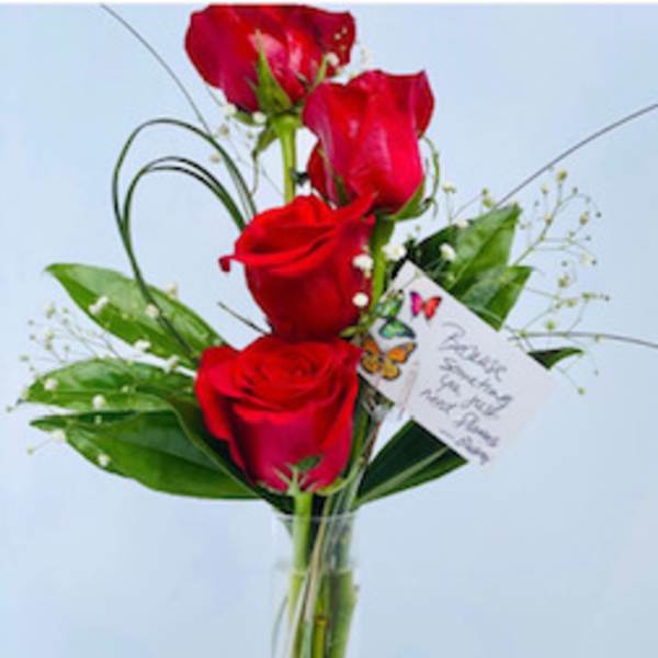 Red roses arranged in a clear glass vase with greenery