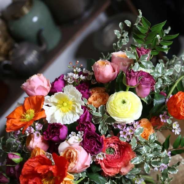 Mixed bouquet of colorful roses and ranunculus with variegated foliage