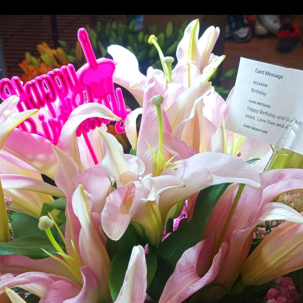 Pink and white lilies with a bright pink Happy Birthday sign