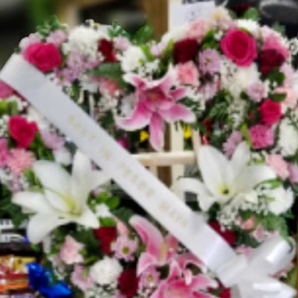 Two pink and white floral wreaths on easels with white ribbons