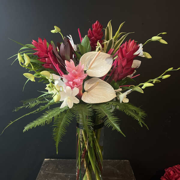 Tropical bouquet with white anthuriums and red ginger in a glass vase