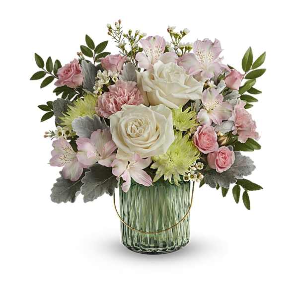 Pastel arrangement of cream roses, pink blooms, and green mums in a green glass vase