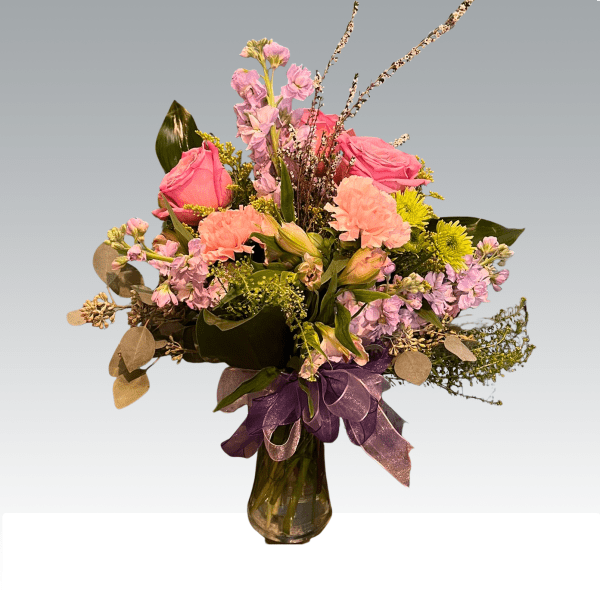 Pink and peach mixed bouquet in a glass vase with a purple ribbon