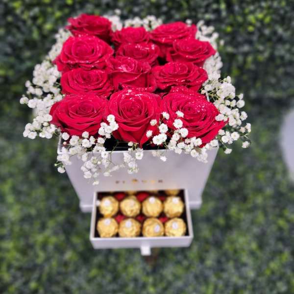 Red roses in a white box with baby’s breath and chocolates below