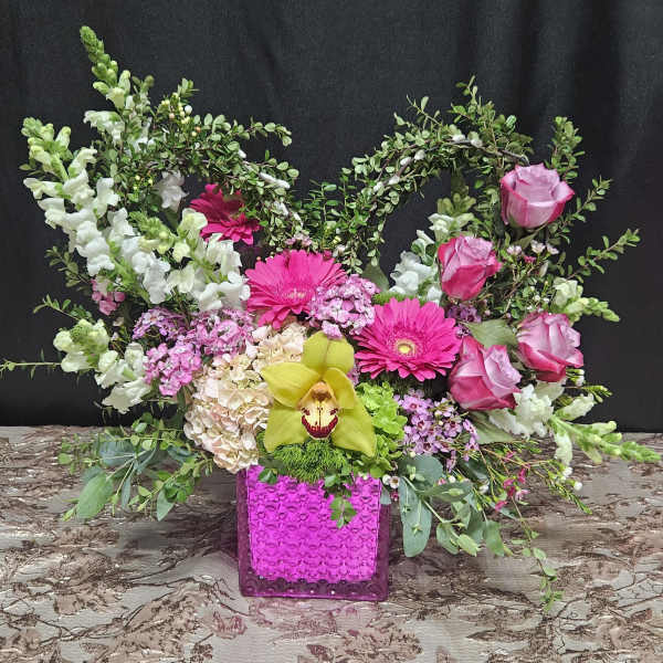 Pink and white floral arrangement in a bright magenta vase
