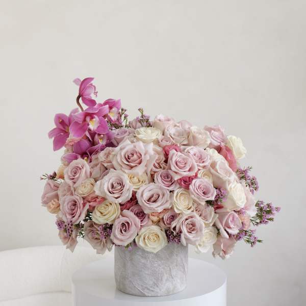 Pink and white rose bouquet with orchids in a gray vase