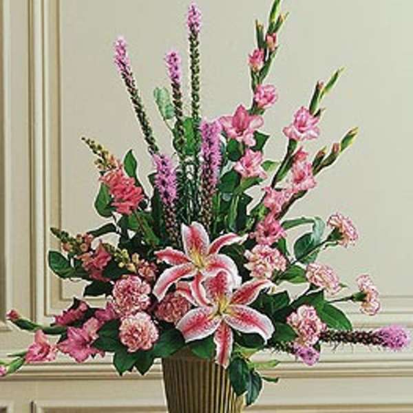 Tall pink floral arrangement with lilies and carnations in a gold-tone container.