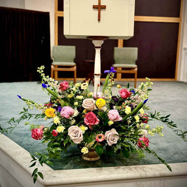 Large colorful altar flower arrangement with roses and mixed blooms in a gold pedestal bowl