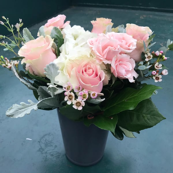 Pink and white roses arranged in a dark vase