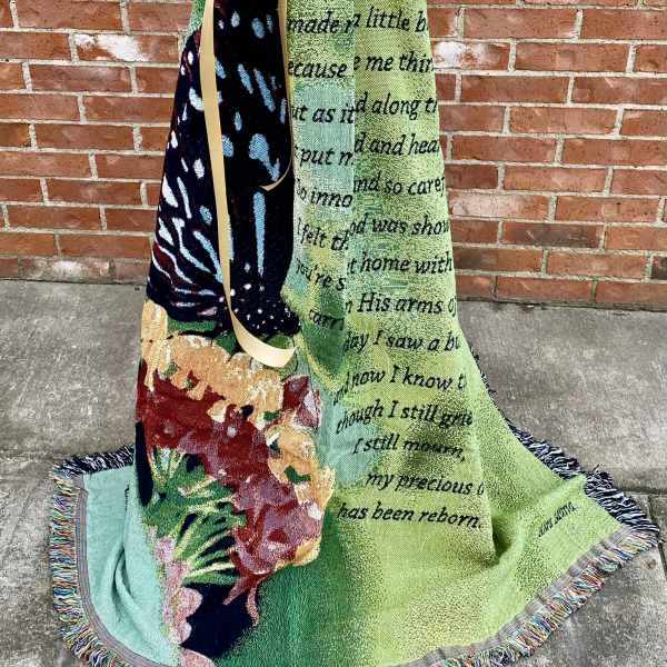 Decorative blanket draped with a large gold bow against a brick wall