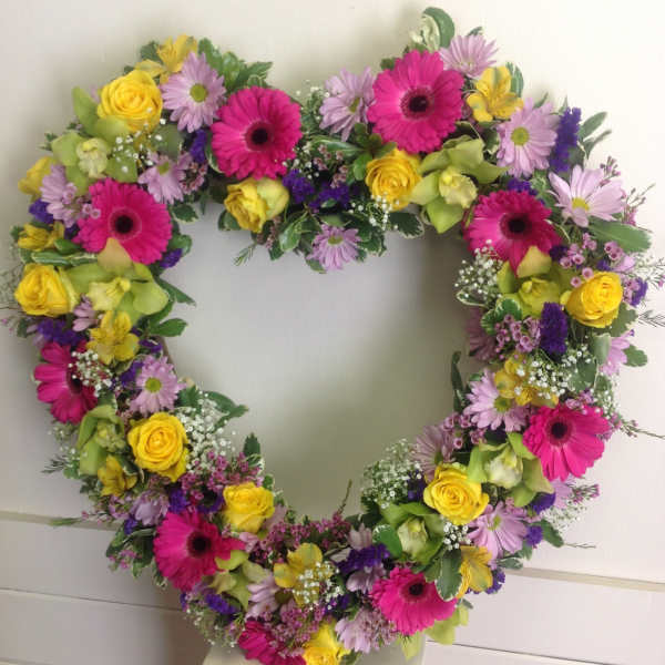 Heart-shaped floral wreath with pink, yellow, and lavender blooms
