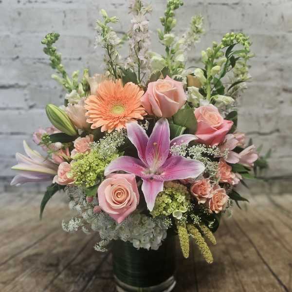 Mixed bouquet with pink lilies, roses, and peach gerbera daisies in a vase