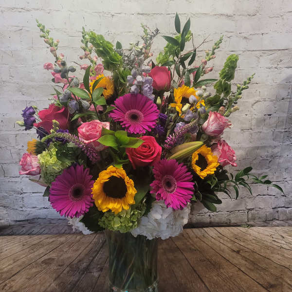 Mixed bouquet in a clear glass vase with pink, yellow, and purple blooms
