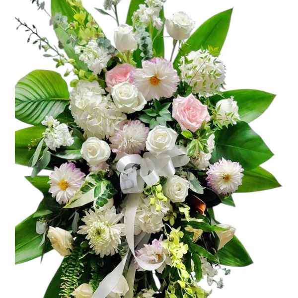 Standing floral spray with white and pale pink flowers on a white ribbon
