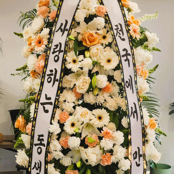 Tall white and peach standing spray with roses, lilies, gerberas, and Korean message ribbons on an easel