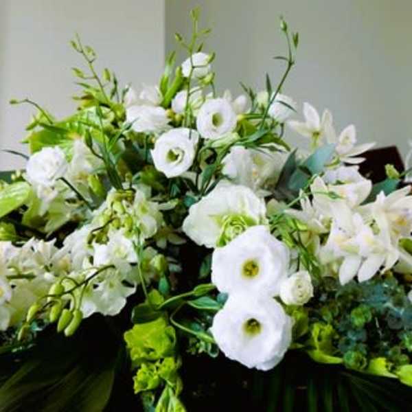 Large white lily and lisianthus spray with green accents displayed in a church setting