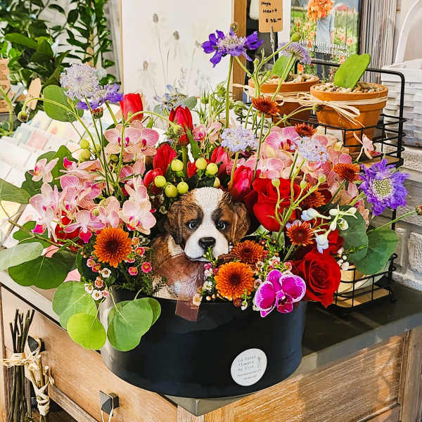 Colorful flower arrangement with a puppy figurine in a black box