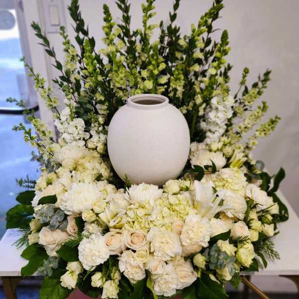 White floral arrangement surrounding a round white urn