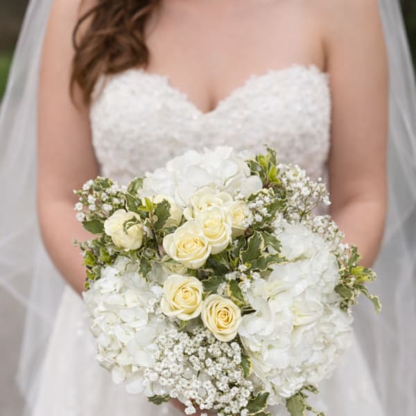 Bride holding a white bouquet with roses and hydrangeas