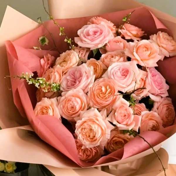 Bouquet of blush and peach roses wrapped in pink paper