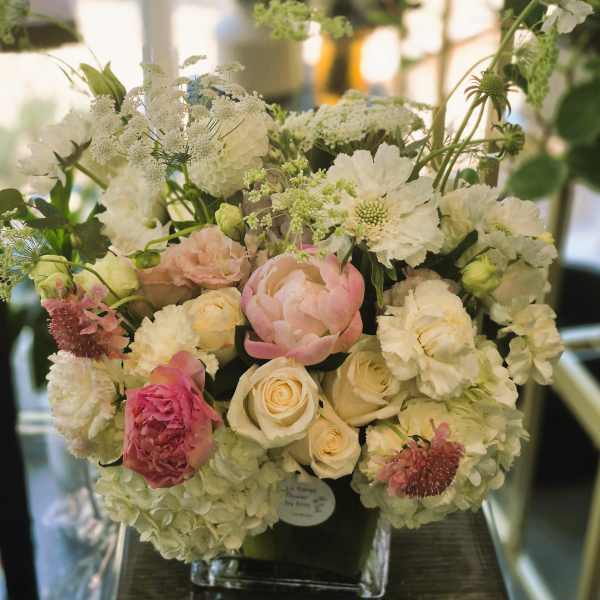 White and blush floral arrangement in a clear vase