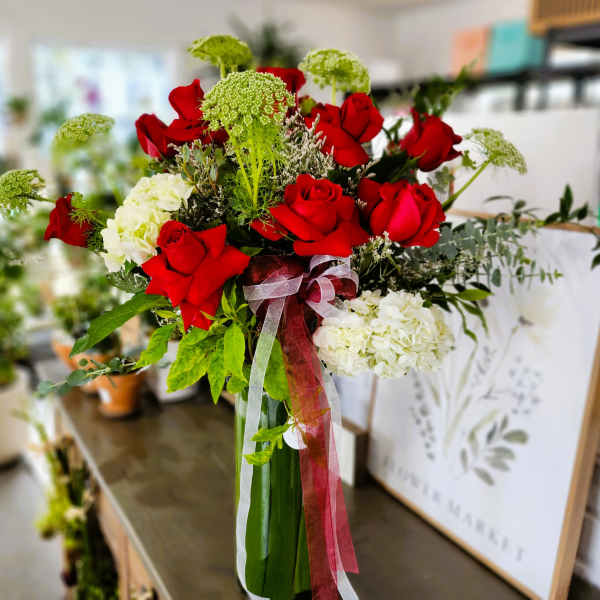 Bouquet of red roses and white hydrangeas with ribbon in a glass vase