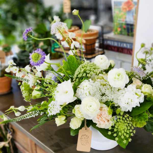 White and pale green floral arrangement in a white container