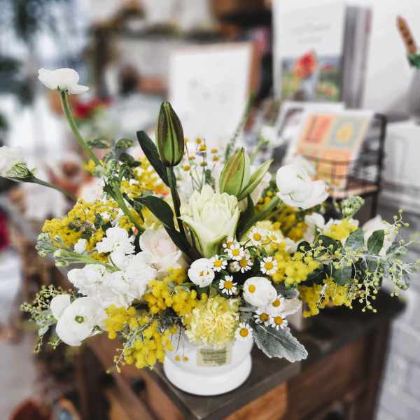 White and yellow floral arrangement in a white vase