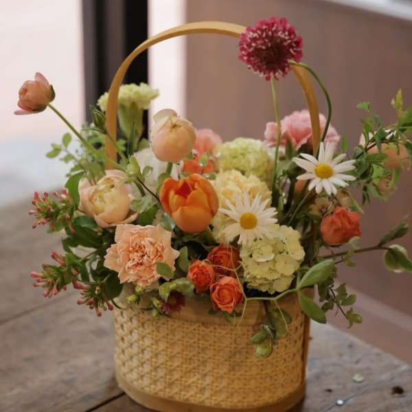 Basket arrangement with orange, peach, pink, and white flowers