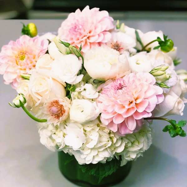 Pink and white flowers arranged in a green glass vase