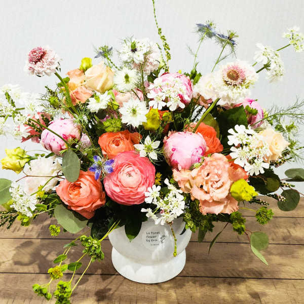 Mixed bouquet of pink, peach, and white flowers in a white vase