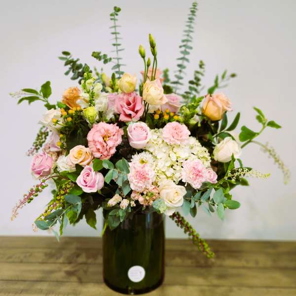 Pink and cream mixed bouquet in a dark glass vase