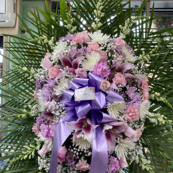Large pink and purple funeral wreath with a lavender ribbon