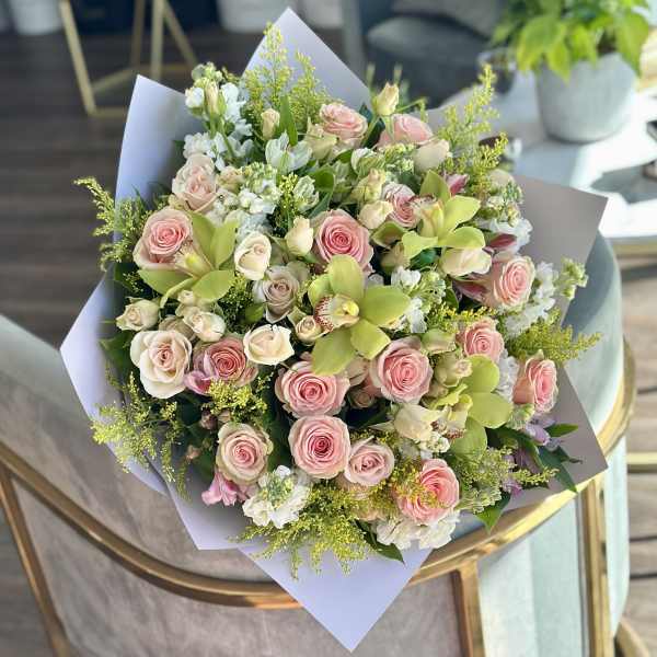 Bouquet of pink and cream roses with green orchids and white filler flowers