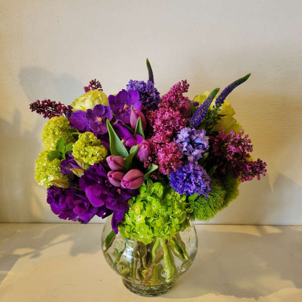 Colorful bouquet in a clear glass vase with purple, pink, yellow, and green blooms
