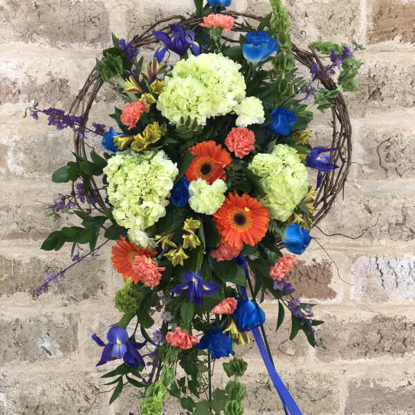 Colorful floral wreath on a stand with blue ribbon