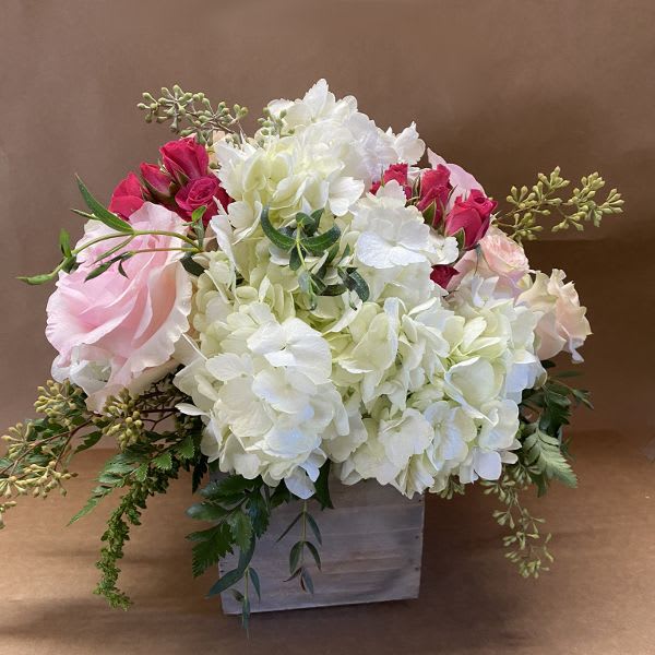 Pink roses and white hydrangeas arranged in a square vase