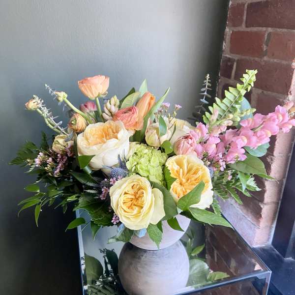 Mixed bouquet of peach and cream roses in a gray vase