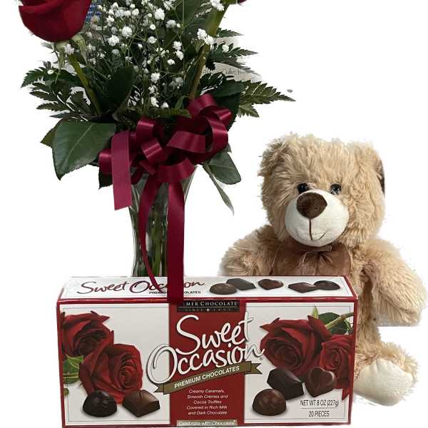 Red roses in a vase with a teddy bear and chocolate box