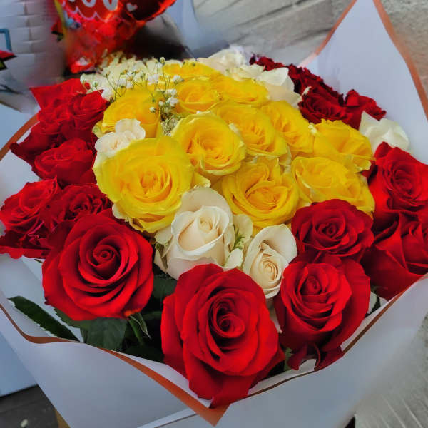Bouquet of red, yellow, and white roses wrapped in white paper