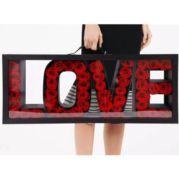 Black box with red roses arranged to spell LOVE