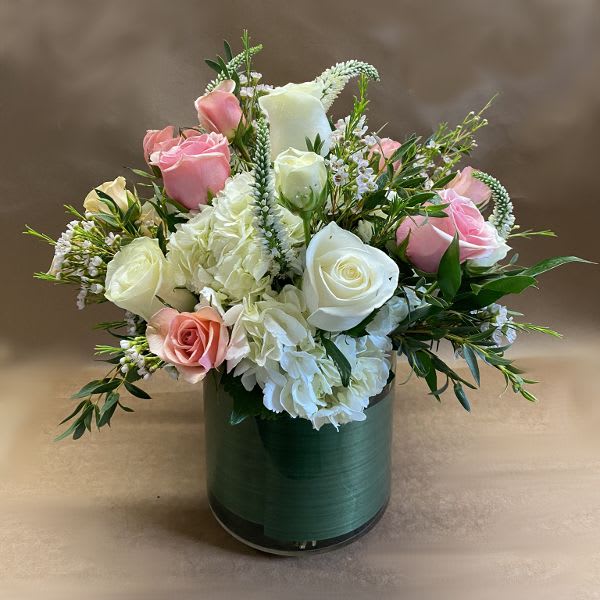 Pink and white roses arranged in a green cylindrical vase