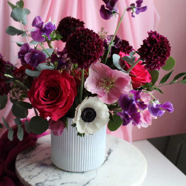 Pink and purple floral arrangement in a white ribbed vase